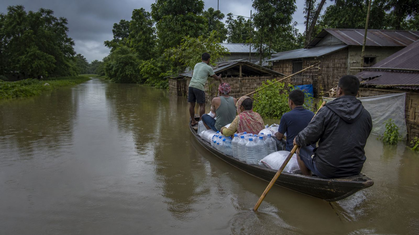 Families and volunteers move essential supplies through floodwater